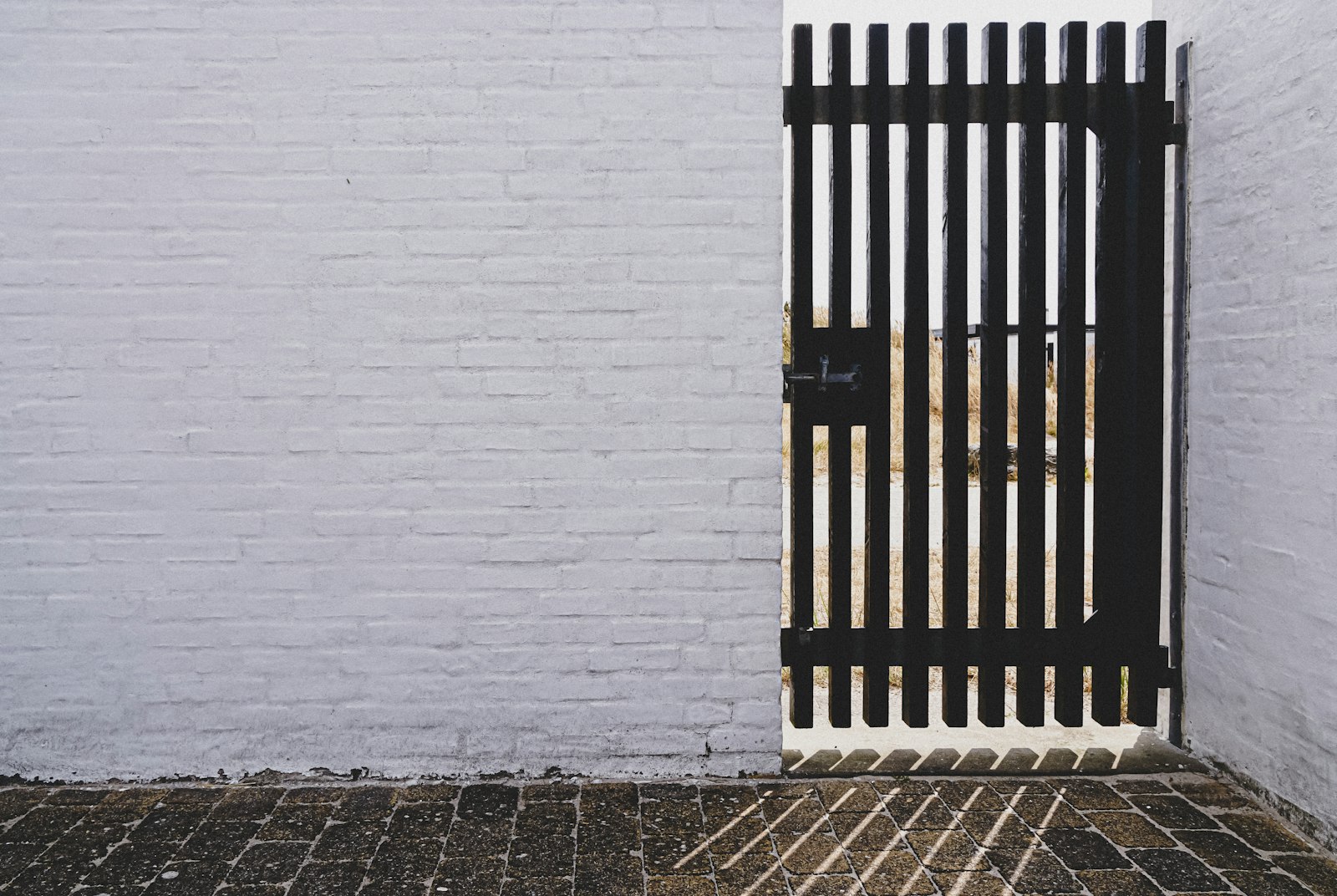 Portão pedonal metálico preto num muro branco